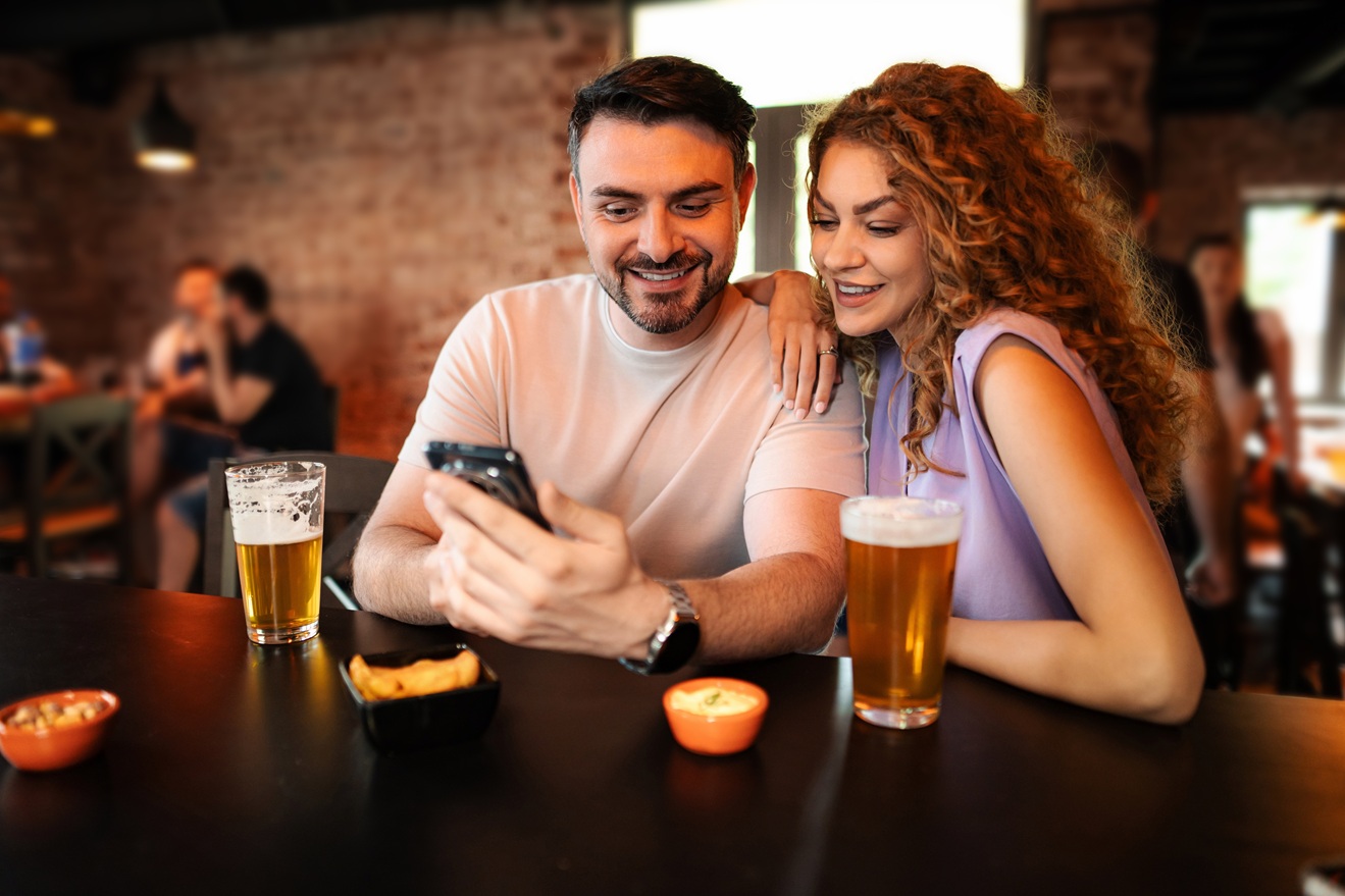 Pareja disfrutando en el bar con cerveza y PulsoBet